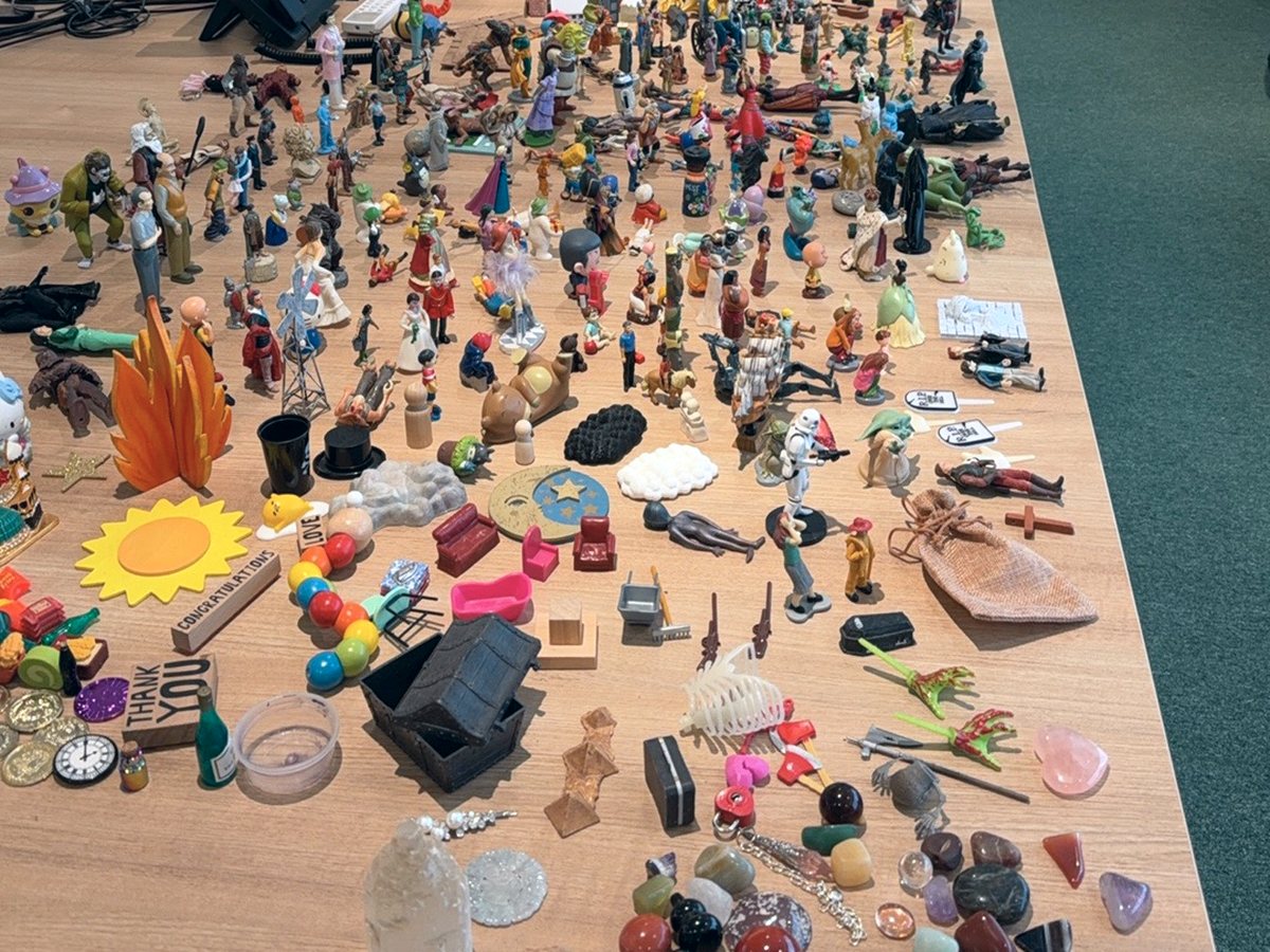 Miniature figures and objects laid out for expressive therapy work
